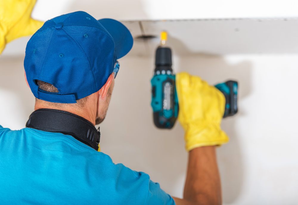 Apartment Remodeling Works. Caucasian Contractor Worker with Power Tool Building Drywall Element.